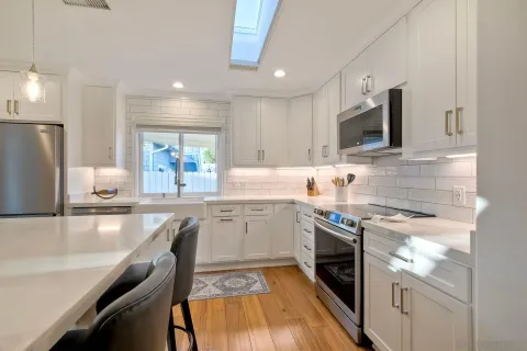 a kitchen with stainless steel appliances kitchen island granite countertop a stove top oven a sink a dining table and chairs