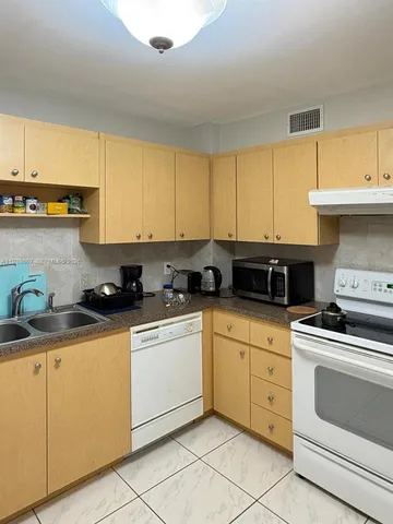 a bed sitting in a kitchen with a refrigerator