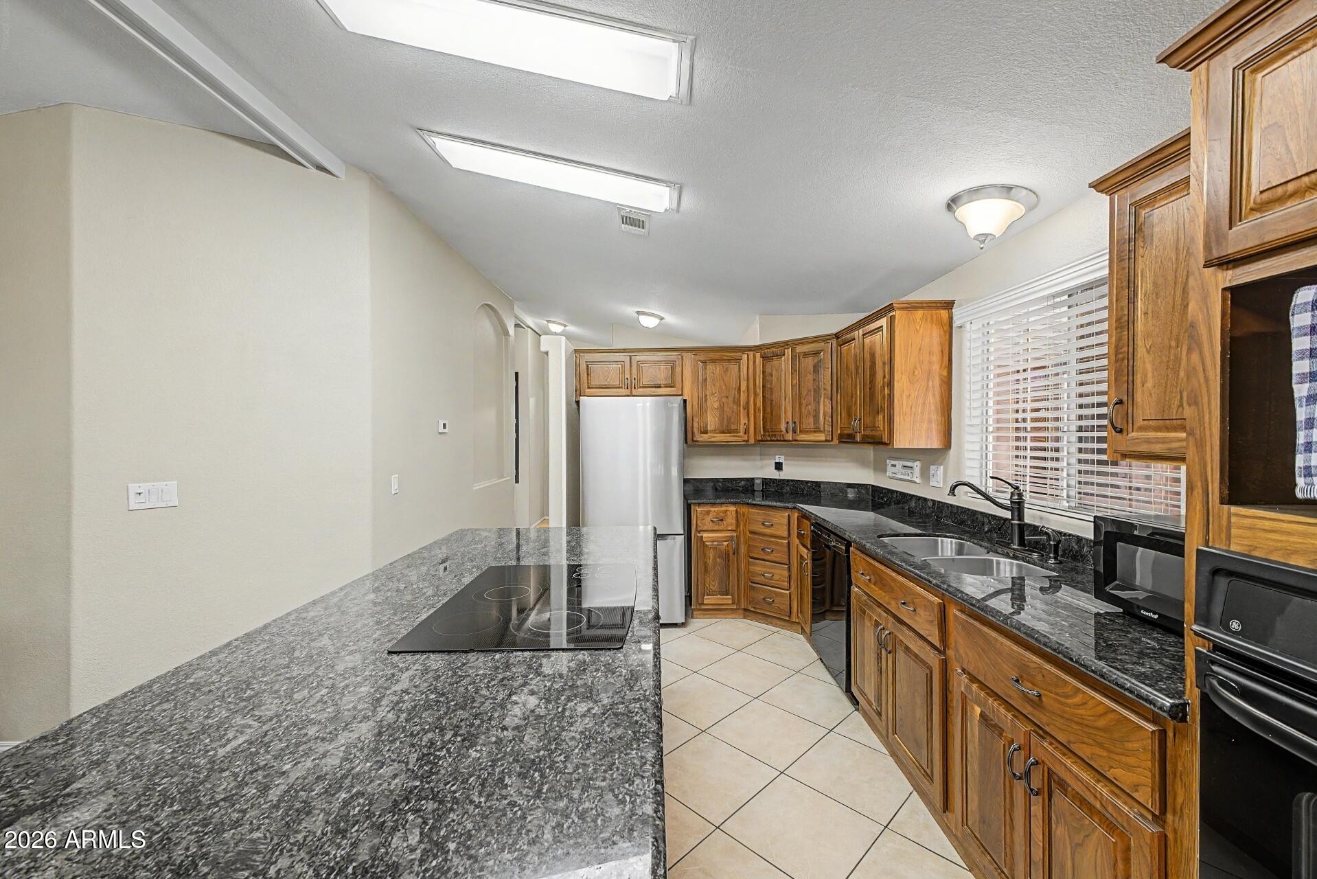 2550 South Ellsworth Road, Unit 46 Mesa, AZ 85209 - Photo 6 of 46 a large kitchen with kitchen island granite countertop a large counter top a sink a stove a refrigerator and cabinets
