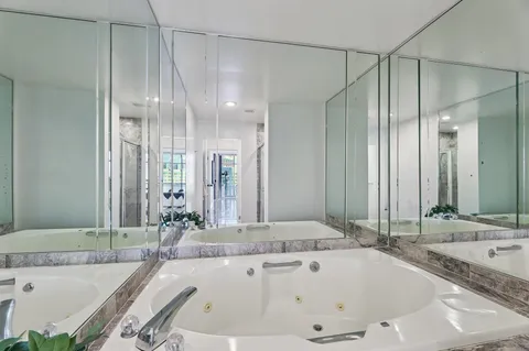 a bathroom with a tub a sink and mirrors
