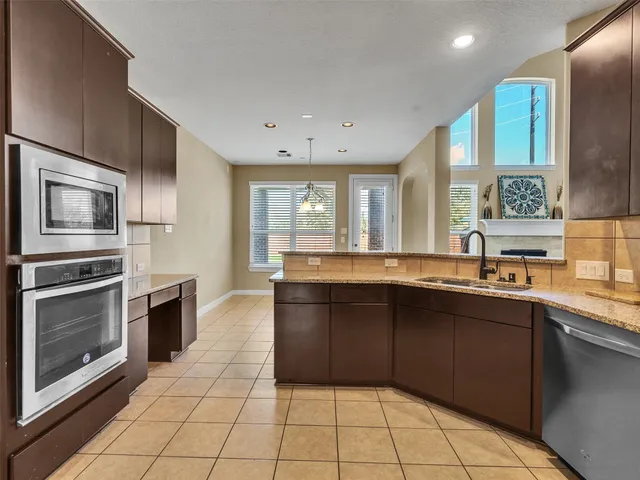 a large kitchen with stainless steel appliances granite countertop a stove a sink and a microwave