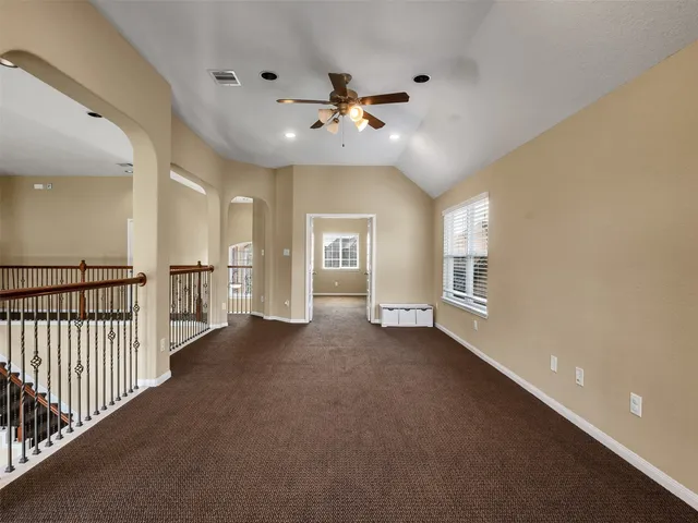 an empty room with windows and ceiling fan