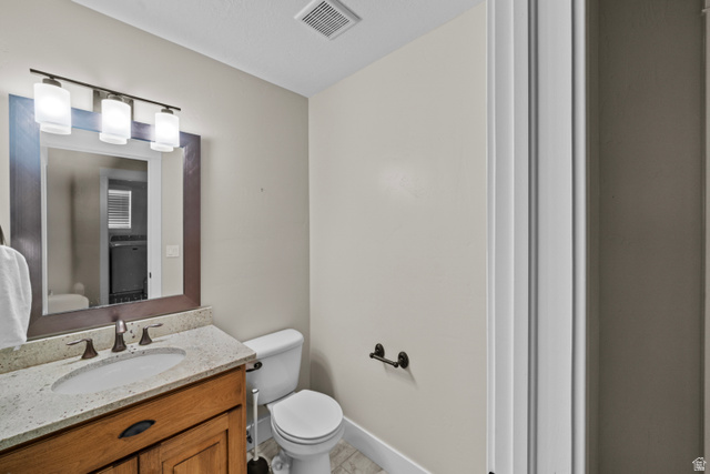 564 Spring Meadow Lane Farmington, UT 84025 - Photo 26 of 31 Wood-finish vanity with an undermount sink, light-toned countertop, and bronze-finish faucet