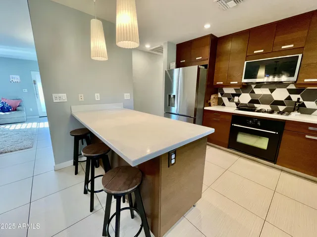 a kitchen with stainless steel appliances kitchen island a table chairs in it and wooden floors