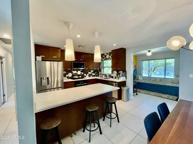 a kitchen with stainless steel appliances kitchen island granite countertop a table chairs in it and wooden floors