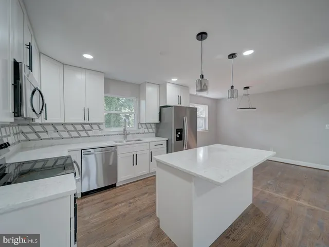 a kitchen with a sink white cabinets and stainless steel appliances