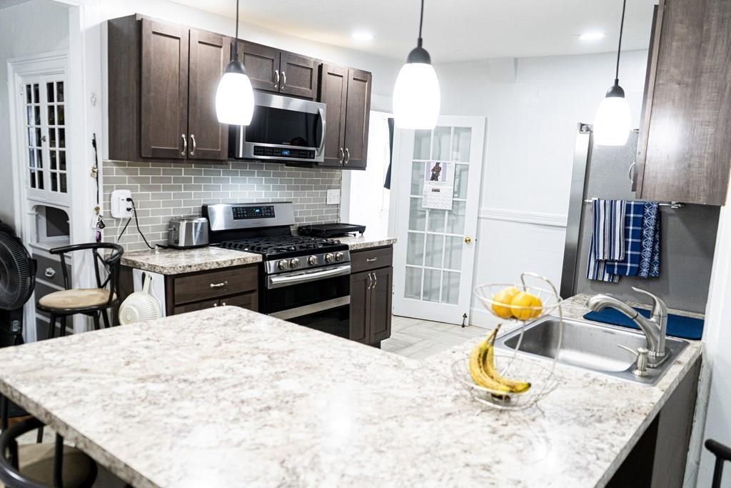 107 Ranney Street Springfield, MA 01108 - Photo 5 of 21 a kitchen with stainless steel appliances kitchen island granite countertop a sink dishwasher stove and refrigerator with wooden floor