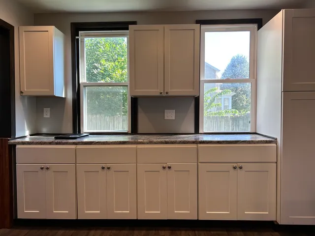 a kitchen with granite countertop white cabinets and a window