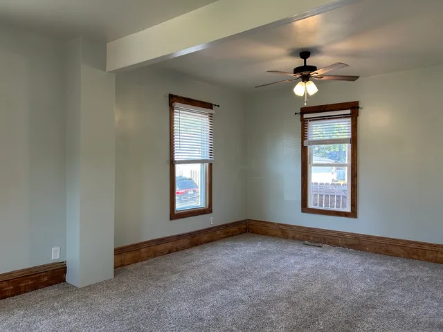 an empty room with windows and fan
