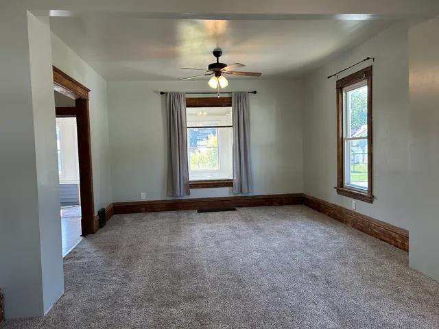 an empty room with windows and chandelier fan