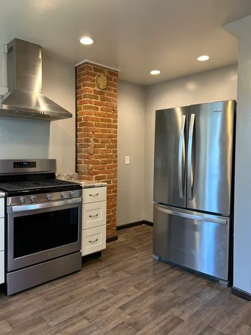 a kitchen with stainless steel appliances granite countertop a hardwood and a refrigerator