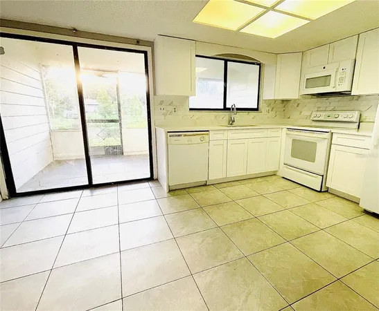 a white kitchen with a sink a stove a refrigerator and white cabinets next to a window