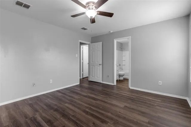an empty room with wooden floor ceiling fan and windows