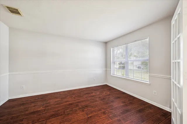 an empty room with wooden floor and windows
