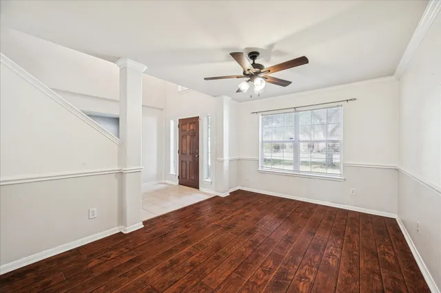 a view of an empty room with a window and wooden floor