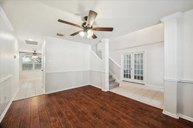 an empty room with wooden floor fan and windows
