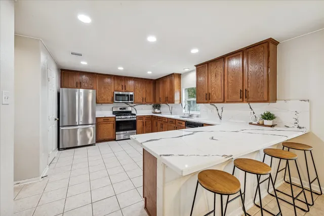 a kitchen with stainless steel appliances granite countertop a refrigerator a stove a sink and a microwave