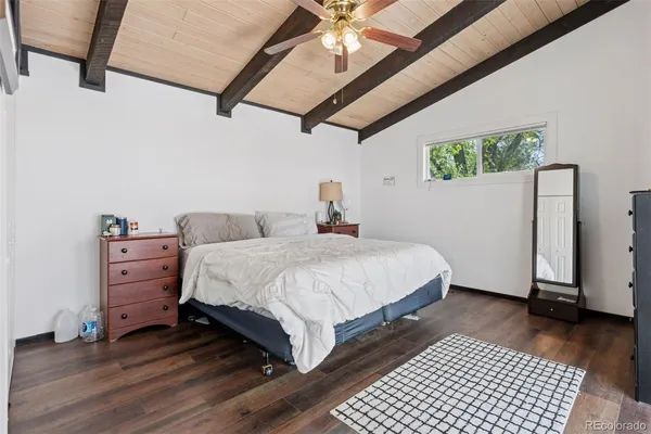 a bedroom with a bed wooden floor and large window