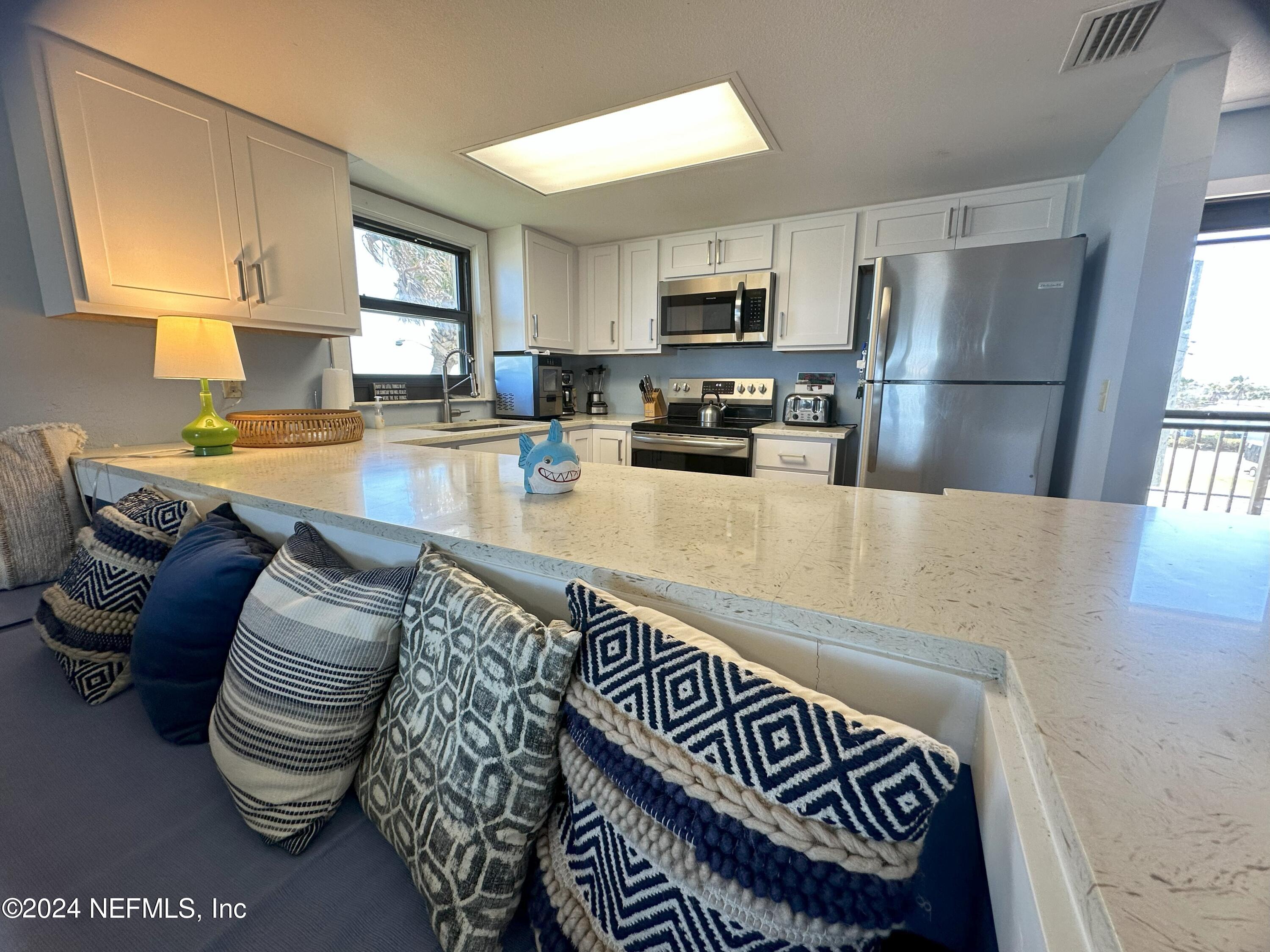 2100 Ocean Shore Boulevard, Unit 3010 Ormond Beach, FL 32176 - Photo 8 of 32 a kitchen with a refrigerator a stove a sink dishwasher and white cabinets with wooden floor