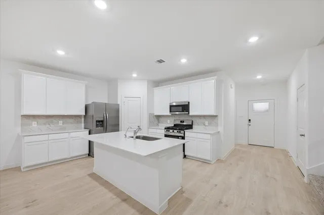 a large white kitchen with a stove a sink dishwasher and a refrigerator with wooden floor