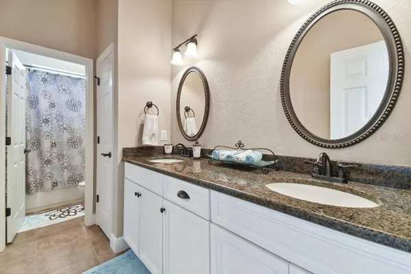 a bathroom with a granite countertop double vanity sinks and a mirror