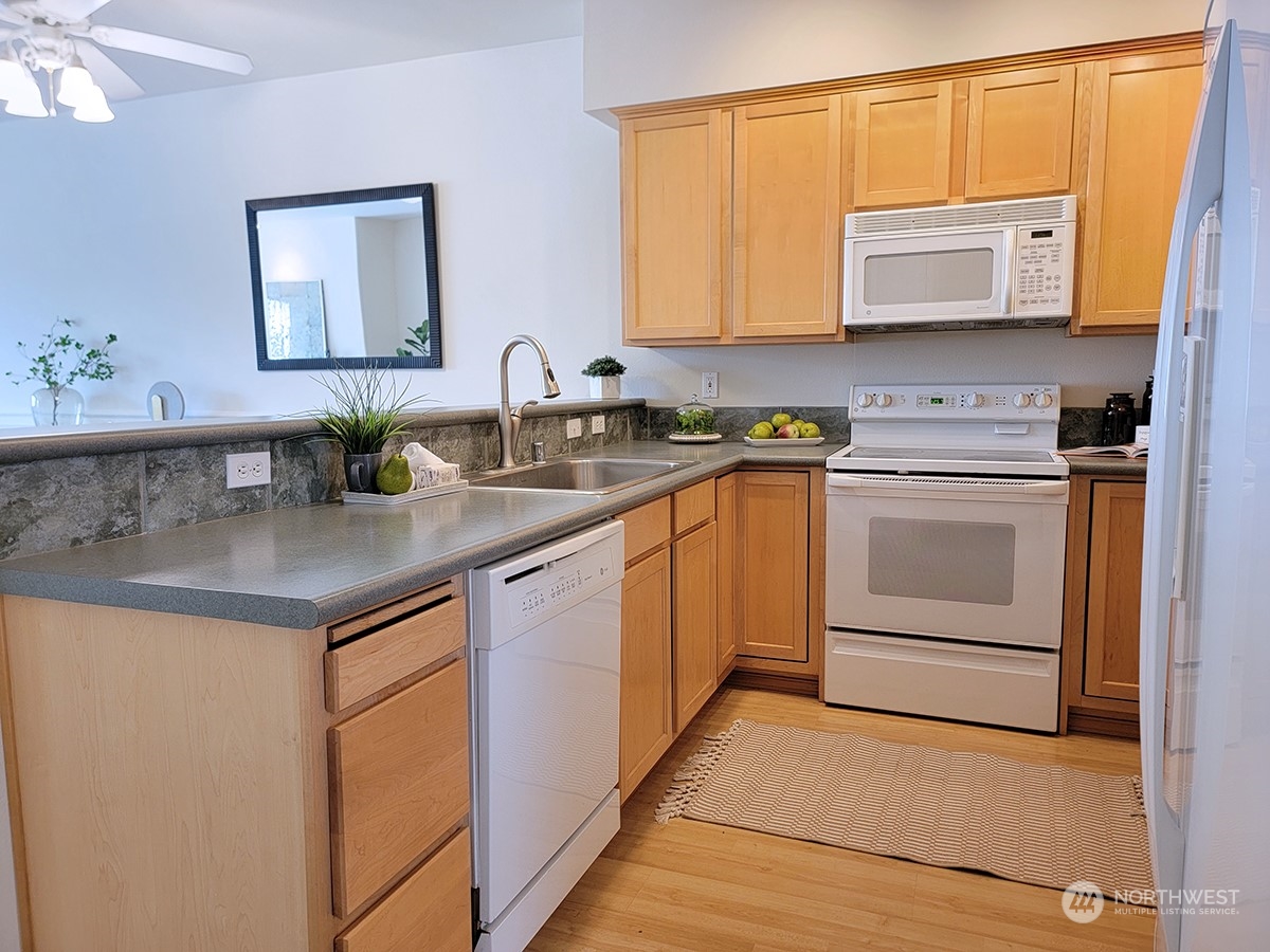 440 Maple Avenue Southwest, Unit A203 Renton, WA 98057 - Photo 11 of 33 a kitchen with stainless steel appliances granite countertop a stove a sink and a microwave