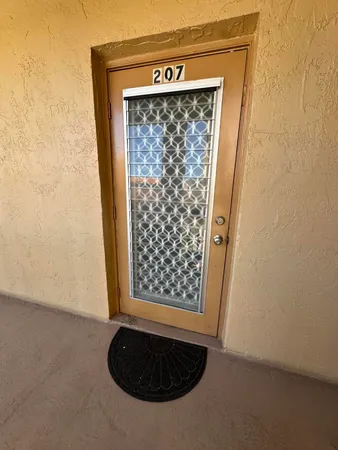 a view of a hallway to an empty room with wooden floor and a kitchen