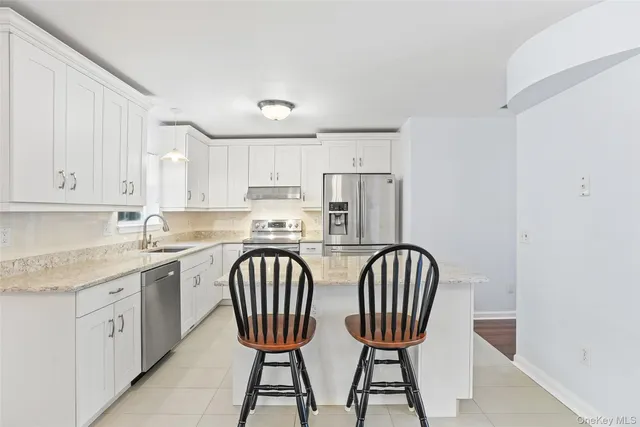 a kitchen with stainless steel appliances granite countertop a table chairs and a refrigerator