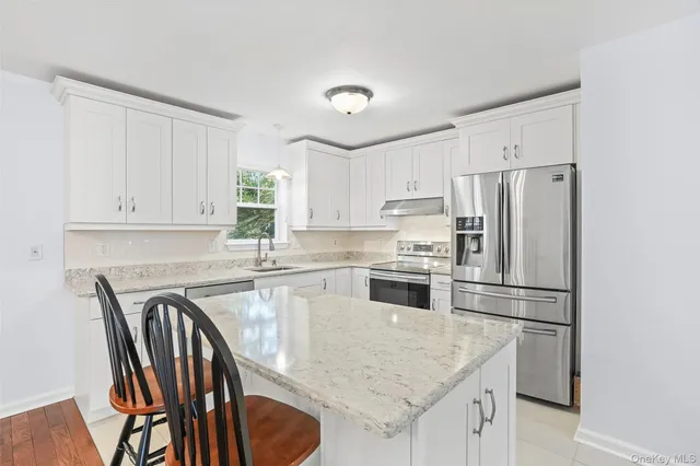 a kitchen with stainless steel appliances granite countertop a refrigerator a stove a sink a dining table and chairs