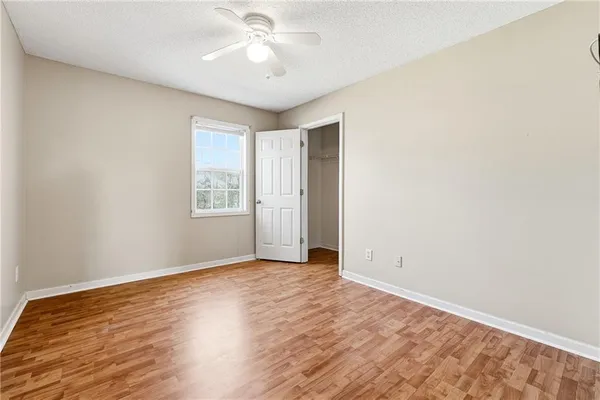an empty room with wooden floor chandelier fan and windows