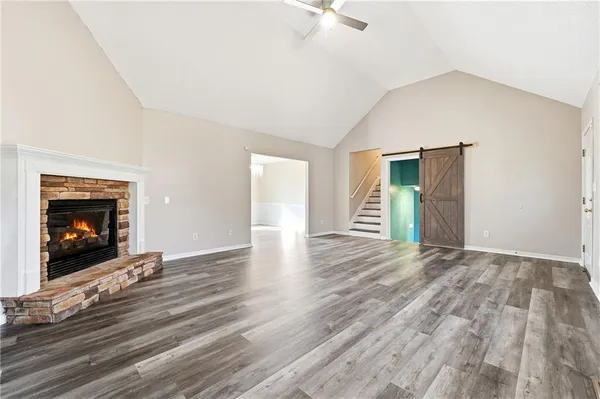 a view of an empty room with wooden floor fireplace and a window