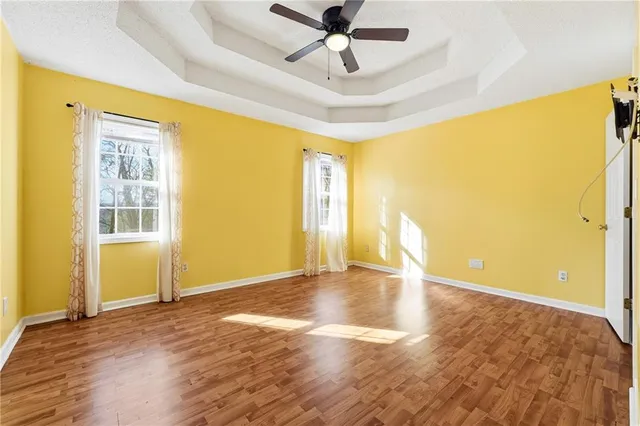 a view of empty room with wooden floor and fan