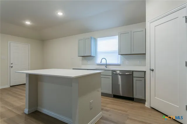 a kitchen with stainless steel appliances cabinets and wooden floor