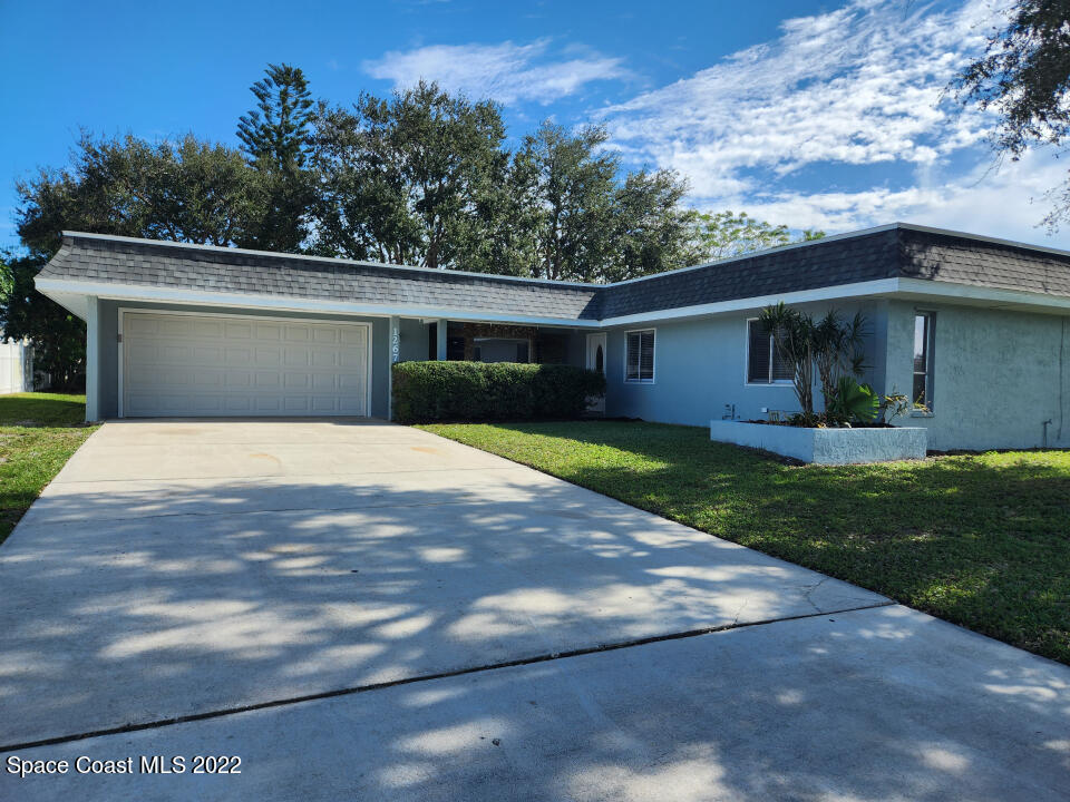 1267 Cotton Road Northeast Palm Bay, FL 32905 - Photo 1 of 30 a front view of a house with garden