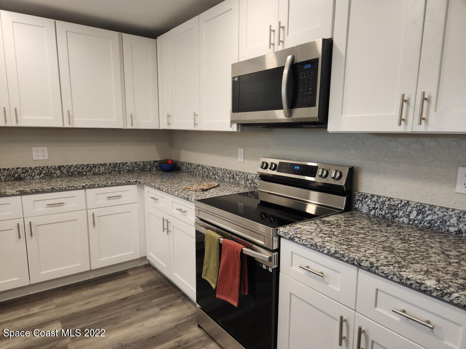 1267 Cotton Road Northeast Palm Bay, FL 32905 - Photo 12 of 30 a kitchen with stainless steel appliances granite countertop white cabinets granite counter tops and a hard wood floors