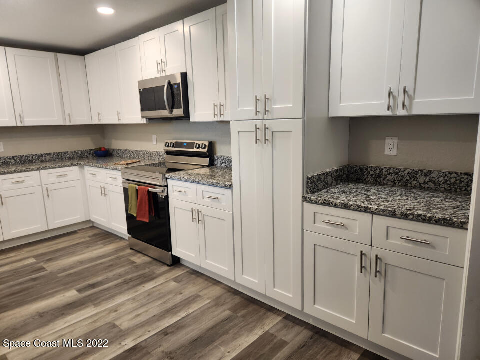 1267 Cotton Road Northeast Palm Bay, FL 32905 - Photo 2 of 30 a kitchen with stainless steel appliances granite countertop a stove a sink and a white cabinets