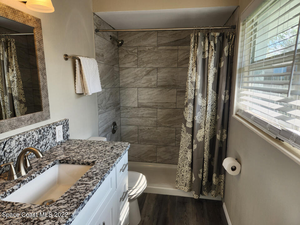 1267 Cotton Road Northeast Palm Bay, FL 32905 - Photo 3 of 30 a bathroom with a granite countertop sink a toilet a mirror and shower