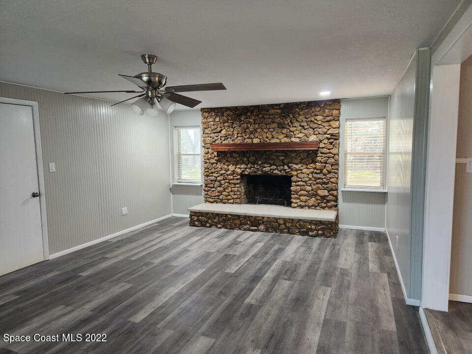 1267 Cotton Road Northeast Palm Bay, FL 32905 - Photo 4 of 30 a view of an empty room with wooden floor fireplace and a window