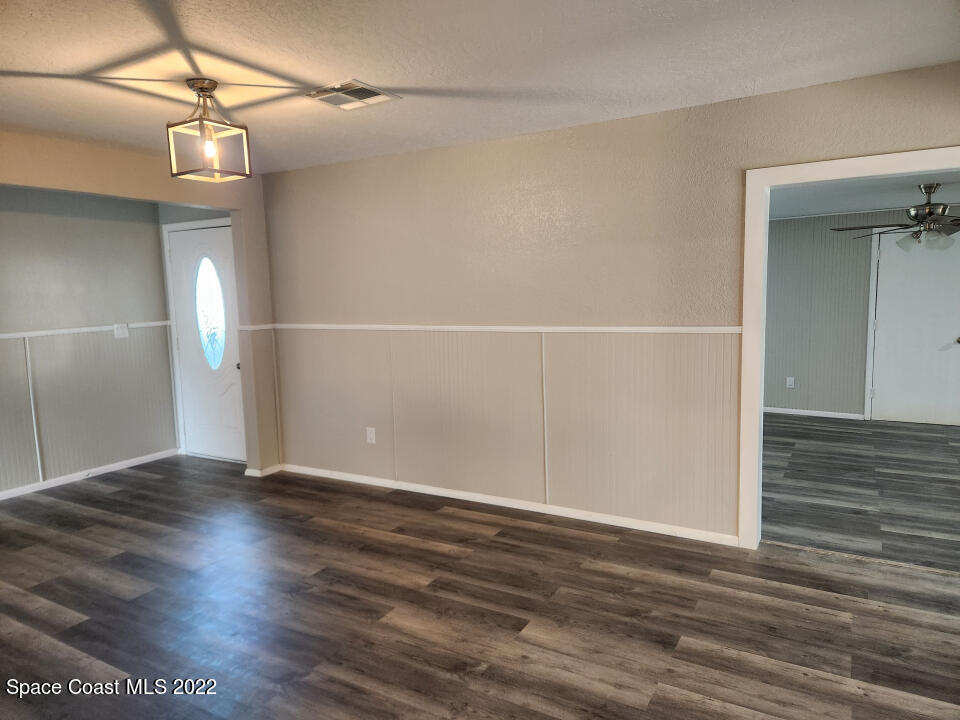 1267 Cotton Road Northeast Palm Bay, FL 32905 - Photo 6 of 30 an empty room with wooden floor chandelier fan and windows
