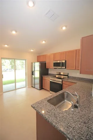 a kitchen with stainless steel appliances granite countertop a sink a stove and a refrigerator with wooden floor