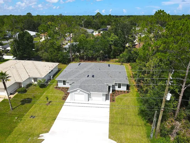 an aerial view of residential houses with outdoor space and trees