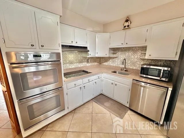 a kitchen with cabinets stainless steel appliances and sink
