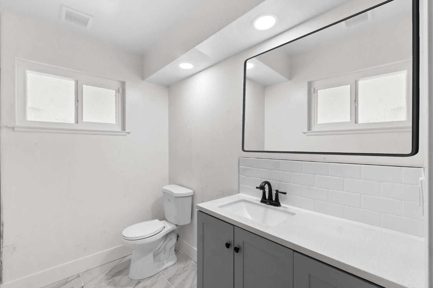 725 West Rialto Avenue Fresno, CA 93705 - Photo 15 of 25 a bathroom with a granite countertop sink a toilet and a window