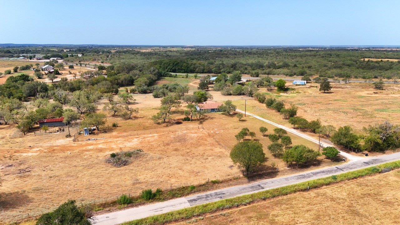 311 Salt Lake Road Luling, TX 78648 - Photo 33 of 37 This aerial perspective shows the water well shed (small blue building) in the left front corner of the property and the tree lined frontage.