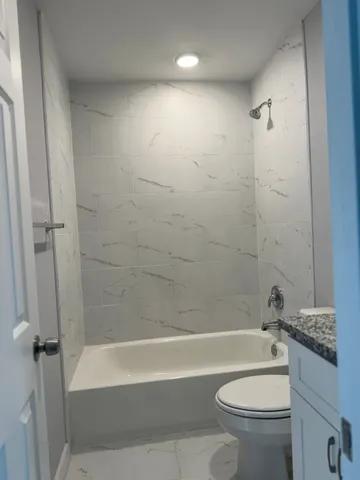 a bathroom with a bathtub shower sink vanity and toilet