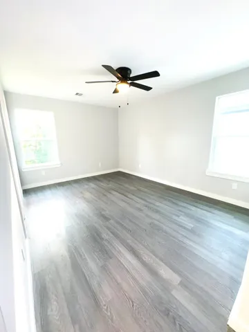 a view of a room with wooden floor and a ceiling fan