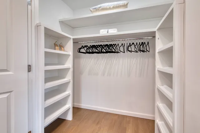 a walk in closet with wooden floor