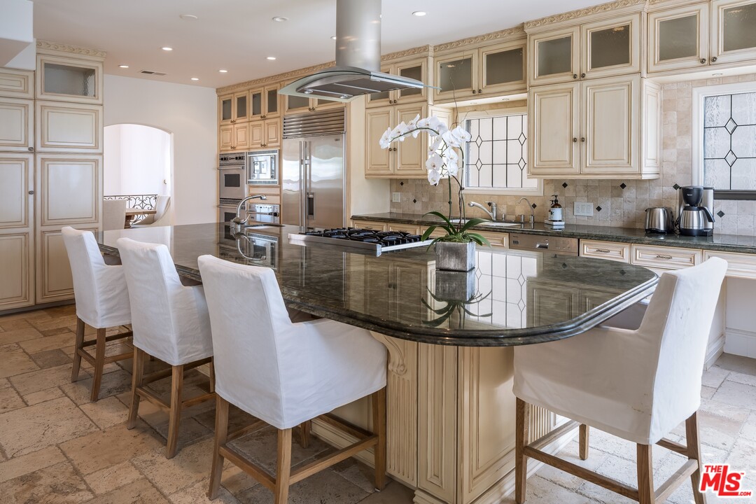 129 Roma Court Marina del Rey, CA 90292 - Photo 14 of 42 a kitchen with stainless steel appliances granite countertop a sink dishwasher a stove a refrigerator a dining table and chairs with wooden floor