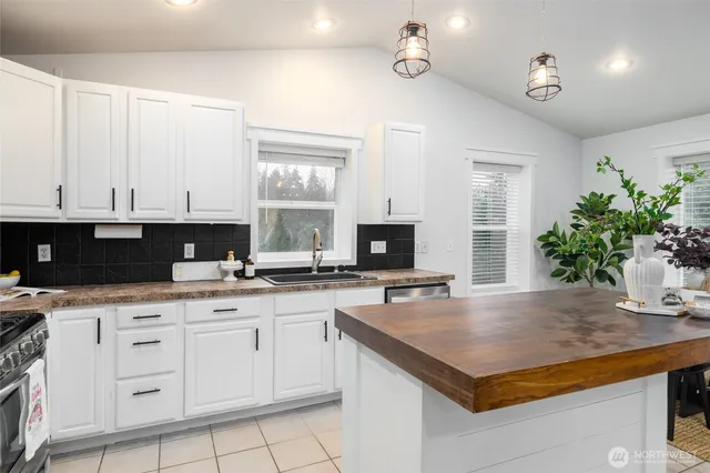 a kitchen with granite countertop a sink white cabinets and black appliances