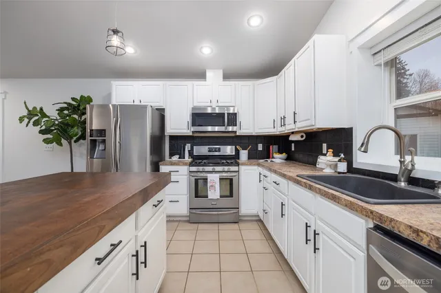 a kitchen with granite countertop white cabinets and stainless steel appliances